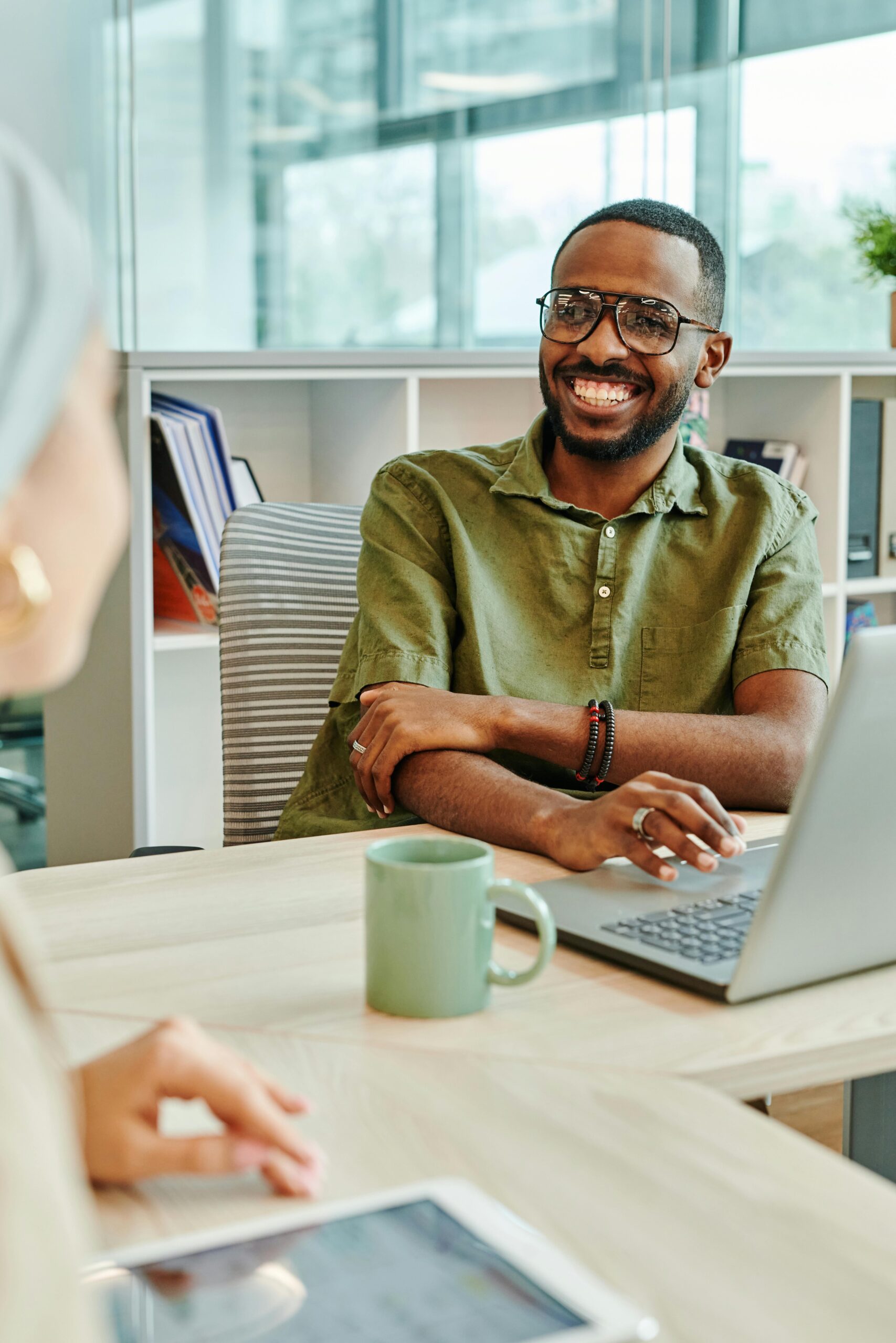 Smiling man working at a computer, interacting with a colleague